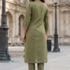Woman in olive green kurta and pants standing on a historic European street.